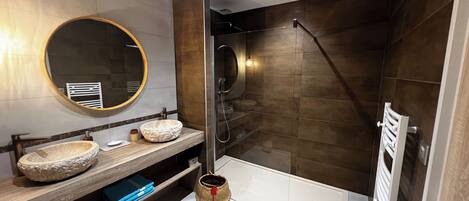 A modern bathroom with two vessel sinks, a large mirror, a glass-enclosed shower, and a white bathtub.