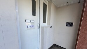 Een gang met een deur waarop '1' staat en een bord met de tekst 'BRIEVEN HIER DEPOSITEREN, BEDANKT'.