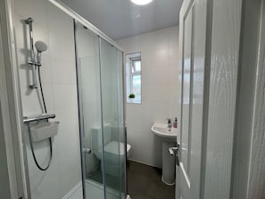 A modern bathroom with a glass-enclosed shower, a toilet, and a sink. - Apartment Sleeps 6 - Wifi & Free Parking (Mitcham)