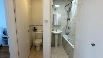 Une salle de bain avec des toilettes, un lavabo et une douche.