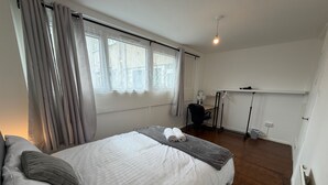 Een slaapkamer met een bed, een bureau, een stoel en een radiator.