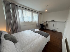 A bedroom with a bed, a desk, a chair, and a radiator. - Apartment Sleeps 6 - Wifi & Free Parking (Mitcham)