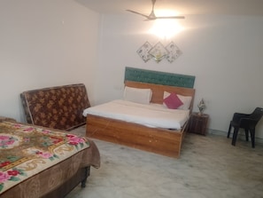 A bedroom with a wooden bed, a floral bedspread, a nightstand, and a ceiling fan.