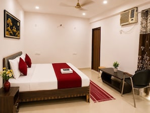 A bedroom with a bed, bedside table, chair, desk, and a ceiling fan.