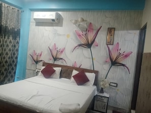 A bedroom with a bed, a nightstand, a wall-mounted air conditioner, and a floral wall mural.