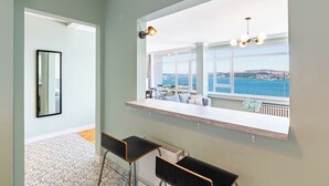 A modern kitchen with a large window overlooking a scenic view, a built-in bar area, and a patterned floor. - Azure Deluxe • Central Bosphorus View Flat (Beyoglu)