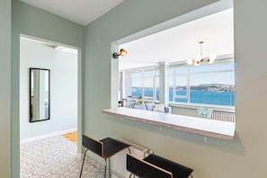 A modern kitchen with a large window overlooking a scenic view, a built-in bar area, and a patterned floor. - Azure Deluxe • Central Bosphorus View Flat (Beyoglu)