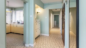 A hallway with patterned flooring, a light blue wall, and a kitchen area with cabinets and a sink. - Azure Deluxe • Central Bosphorus View Flat (Beyoglu)