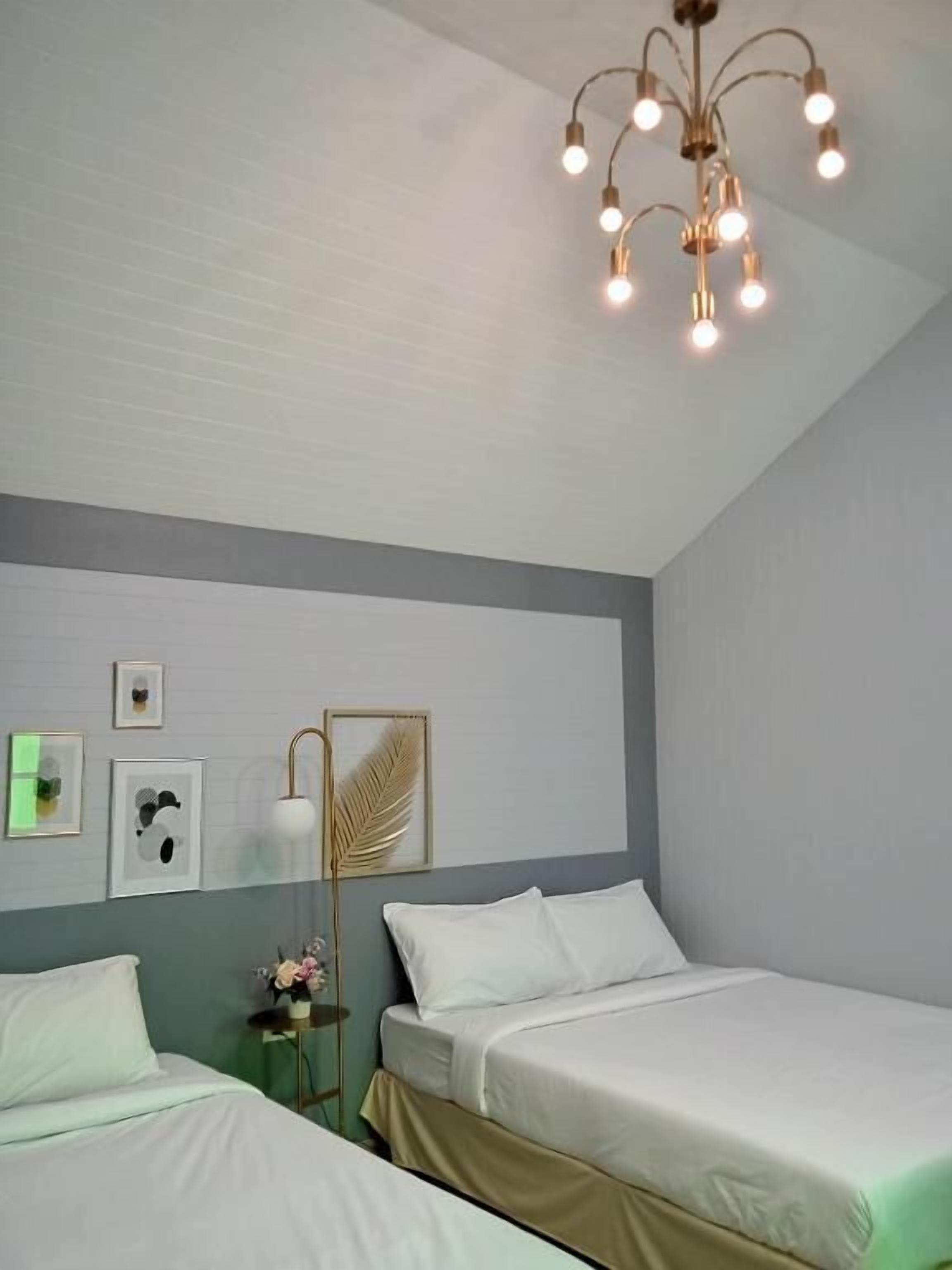 Habitación de hotel con dos camas, una lámpara de pared, cuadros enmarcados y una lámpara del techo.