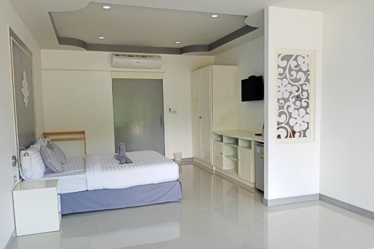 A bedroom with a bed, wardrobe, and a TV mounted on the wall.