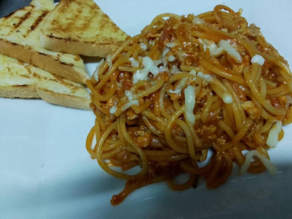Un plato de espagueti y pan a la parrilla.