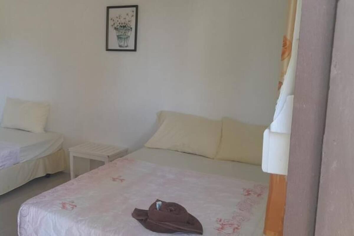 A room with two beds, a small table, and a framed picture on the wall.
