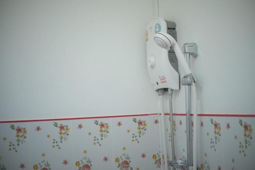 A shower with a floral-patterned wall and a red trim.