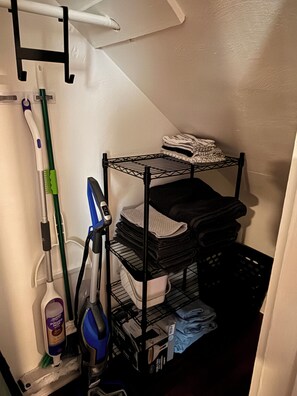 A laundry area with a drying rack, iron, and cleaning supplies.
