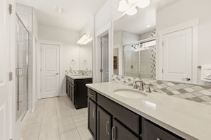 A modern bathroom with a large mirror, a shower, and a vanity with a sink. - The Wandering Key Gather & Unwind, Sleeps 14 (Windsor)