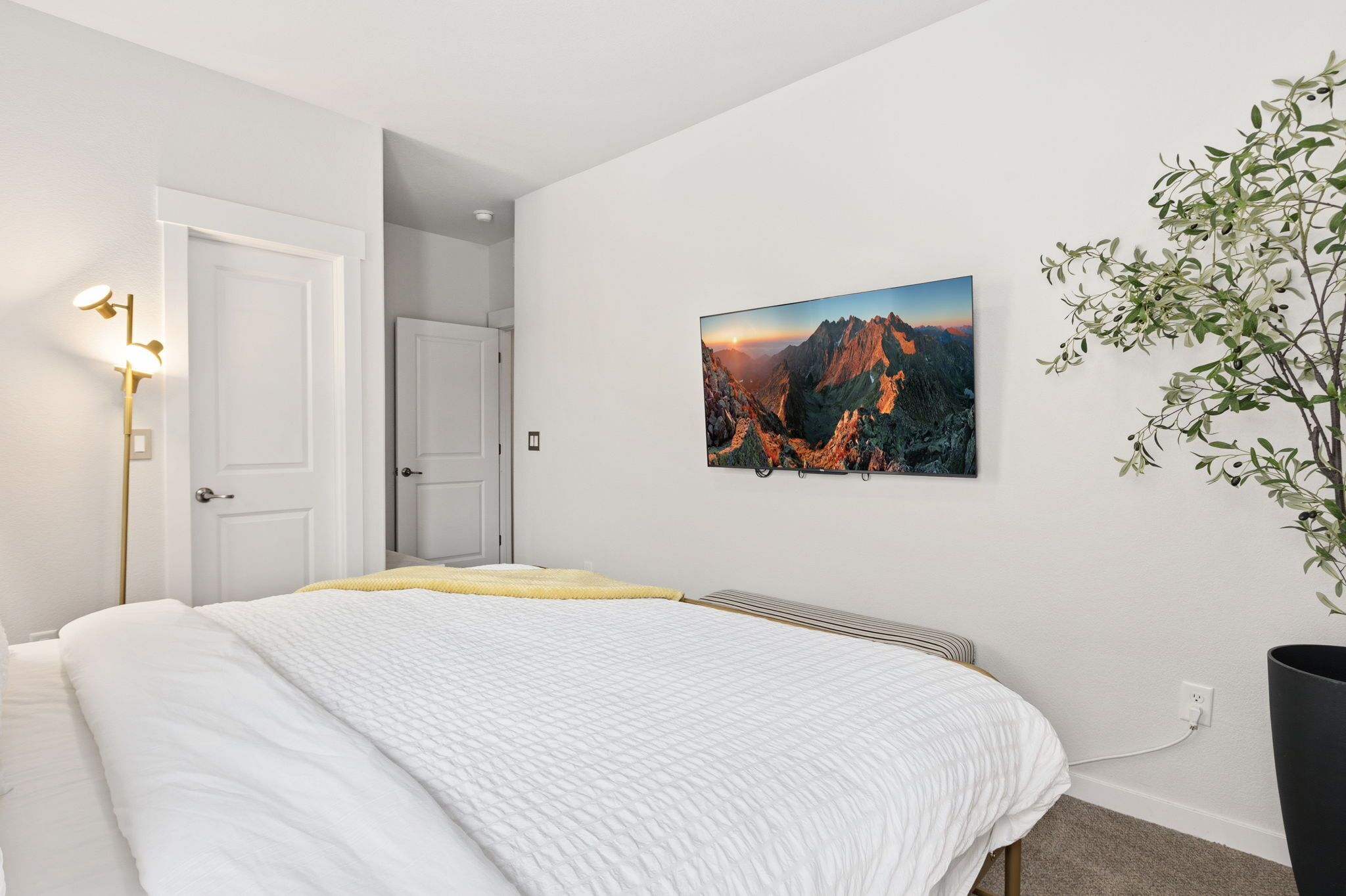 Ein Schlafzimmer mit Bett, einem Wandbild, einer Nachttischlampe und einem Blumentopf.