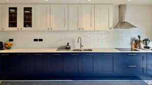 Een moderne keuken met witte bovenkastjes, een blauwe onderkast, een roestvrijstalen spoelbak en een afzuigkap.