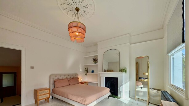 Een slaapkamer met een bed, een open haard, een spiegel en een raam.