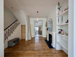 Ein Flur mit Holzboden, einer Treppe, einem Kamin und einem Bücherregal.