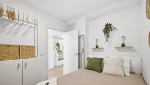 A bedroom with a bed, a wardrobe, a hanging clothes rack, and a door leading to another room. - Accessible Loft | Smart TV | Air Conditioning | Coffee | 2 people (València)