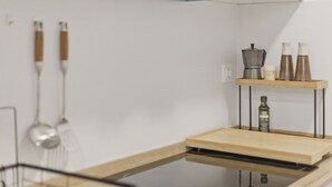 A kitchen with a wooden countertop, a built-in dishwasher, and a shelf with kitchen utensils and bottles. - Accessible Loft | Smart TV | Air Conditioning | Coffee | 2 people (València)