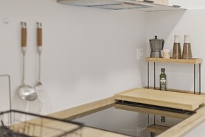 A kitchen with a wooden countertop, a built-in dishwasher, and a shelf with kitchen utensils and bottles. - Accessible Loft | Smart TV | Air Conditioning | Coffee | 2 people (València)