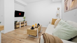 A modern living room with a flat-screen TV, a wooden coffee table, a sofa, and a floor lamp. - Accessible Loft | Smart TV | Air Conditioning | Coffee | 2 people (València)