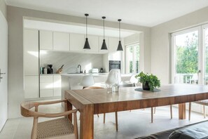 Eine moderne Küche mit weißen Schränken, einem Holztisch und Pendelleuchten.