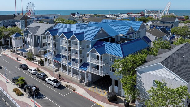 A multi-story hotel with balconies, a parking lot, and a view of the beach and ocean.