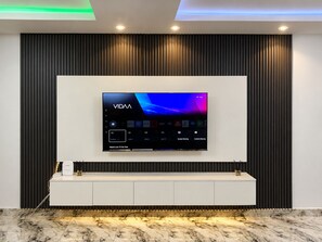 Ein modernes Wohnzimmer mit einem wandmontierten Flachbildfernseher, einer weißen Unterhaltungseinheit und einem Marmorboden.