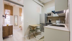 A compact kitchen with a dining area, a microwave, a refrigerator, and a sink. - 2 bedroom apartment in Robador 39 (Barcelona)