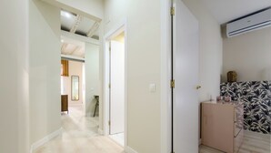 A hallway with a wooden floor, white walls, and a door leading to another room. - 2 bedroom apartment in Robador 39 (Barcelona)