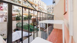 A balcony with a view of a narrow street lined with buildings, a metal railing, and a tiled floor. - 2 bedroom apartment in Robador 39 (Barcelona)