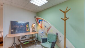 Une pièce comprenant un bureau, une chaise, une planche de surf et un porte-manteau.