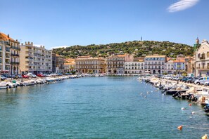 A marina with boats docked, buildings along the water, and a hill in the background. - Holiday Home “Le Bathyscaphe Amical” with Wi-Fi and Air Conditioning (Sète)