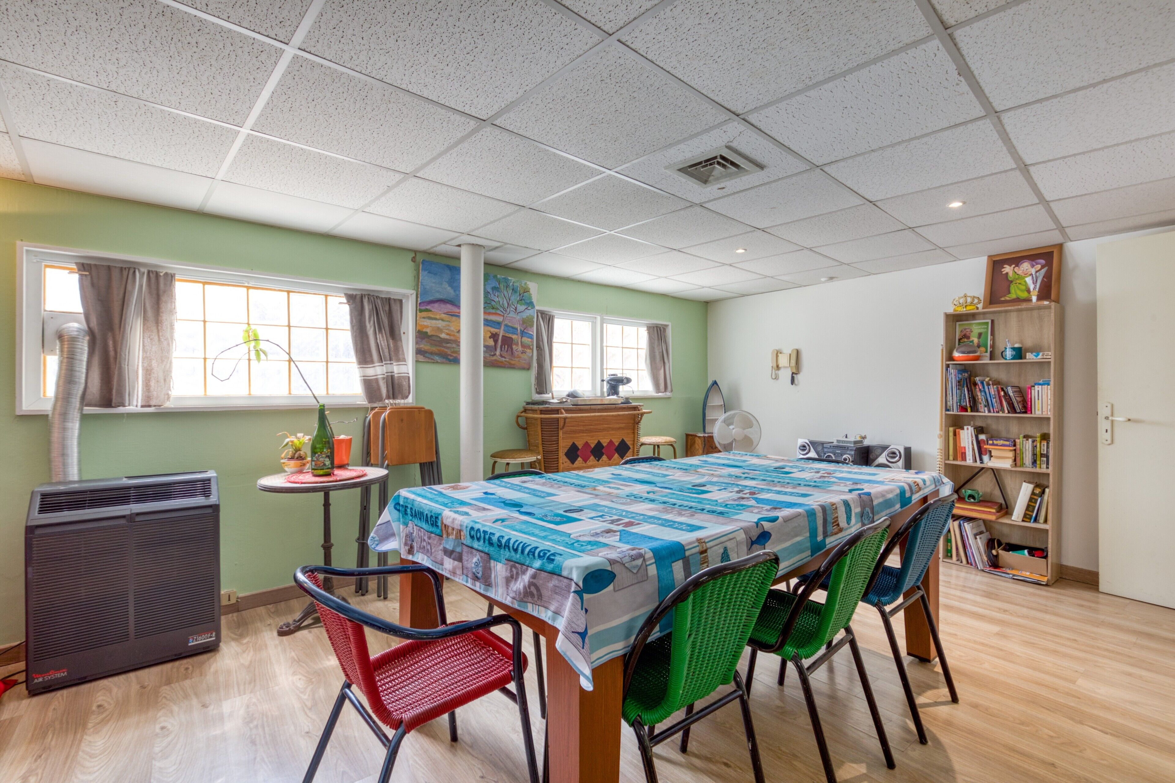 Un comedor con una mesa, sillas, una estantería y un radiador.
