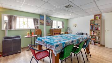 Un comedor con una mesa, sillas, una estantería y un radiador.