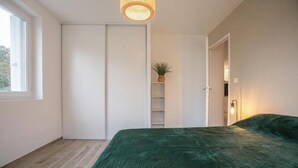A bedroom with a bed, a wardrobe, a shelving unit, and a window. - Elegant 2-bedroom apartment-Near downtown (Périgueux)