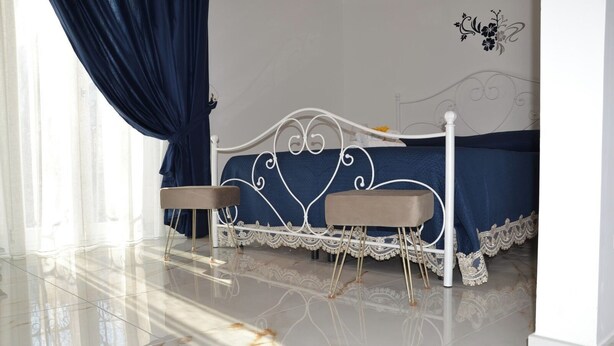 Une chambre à coucher comprenant un lit, deux tables de chevet, une fenêtre avec des rideaux et un élément décoratif mural.
