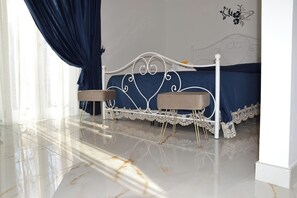Ein Schlafzimmer mit einem Bett, zwei Nachttischen, einem Fenster mit Vorhängen und einer Wanddekoration.