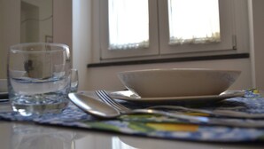 Une table à manger avec un verre d’eau, un bol et des couverts.