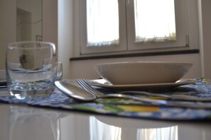 Un tavolo da pranzo con un bicchiere d'acqua, una ciotola e posate.