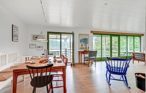 Un espace repas avec une table en bois, des chaises et une vue dégagée grâce à de grandes fenêtres.