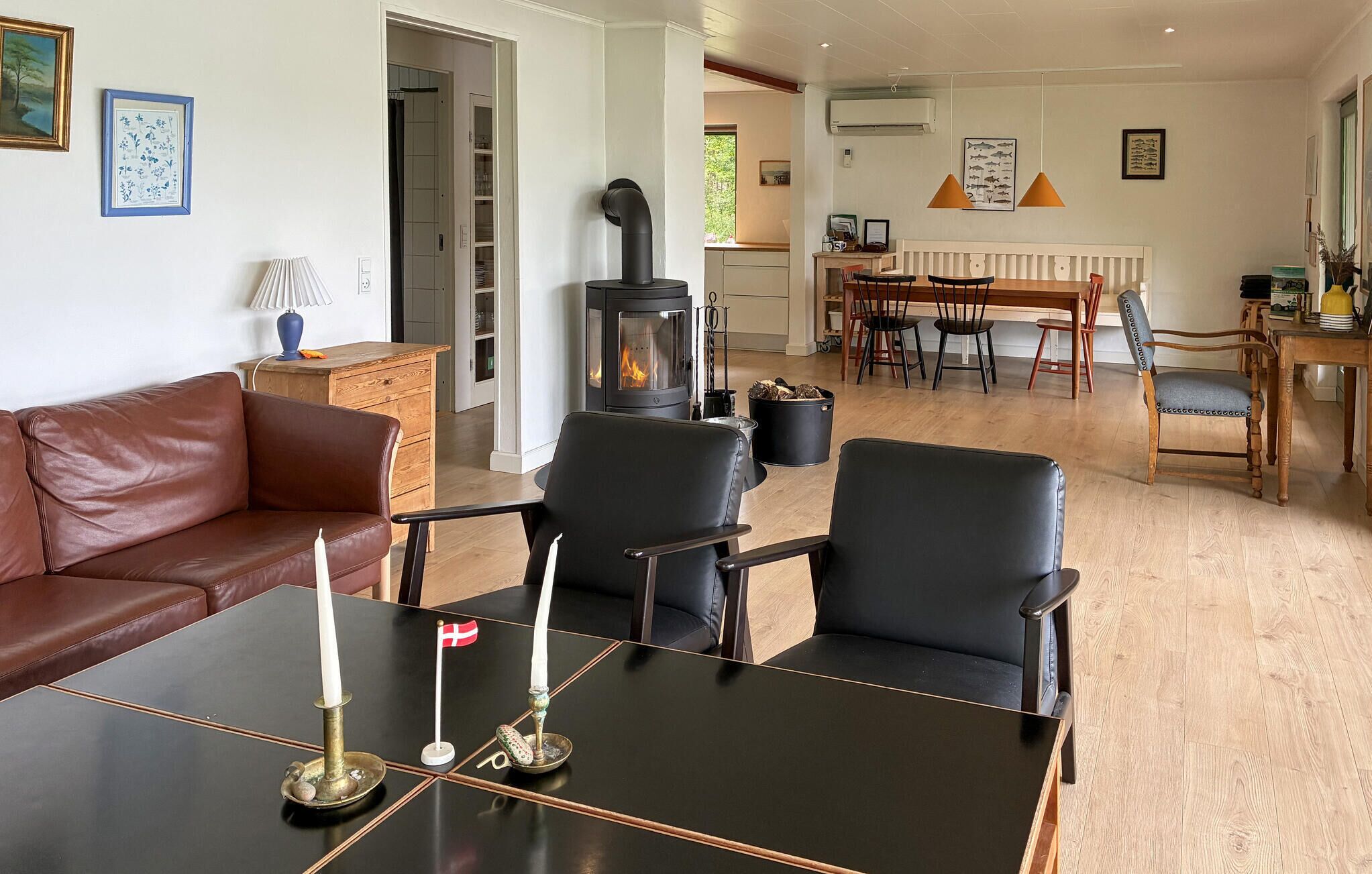 A living room with a sofa, chairs, a table with candles, a fireplace, and a dining area with chairs and a table.