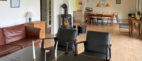 A living room with a sofa, chairs, a table with candles, a fireplace, and a dining area with chairs and a table.