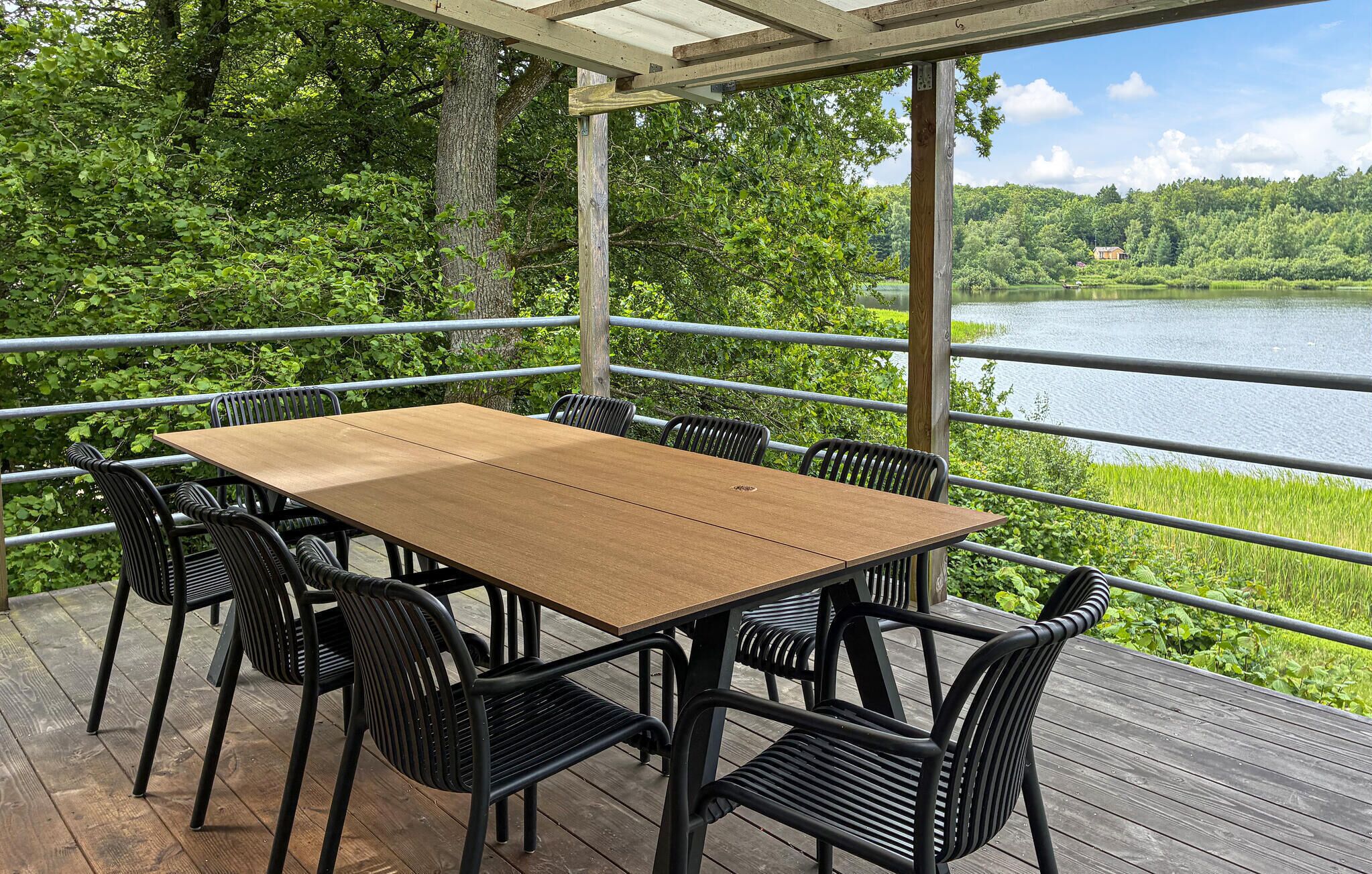 A wooden deck with a table and chairs overlooking a lake.
