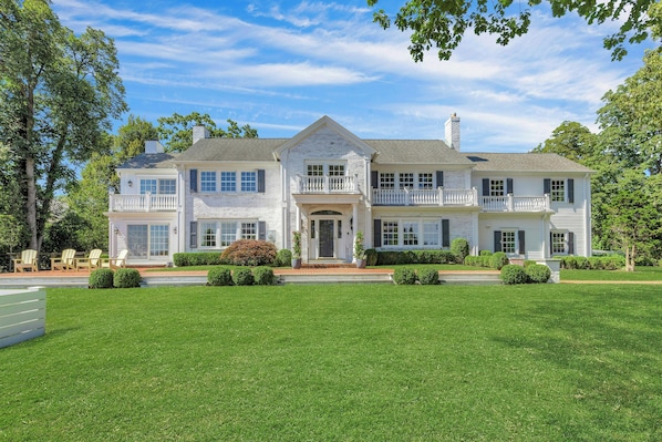 A two-story house with a front porch, a balcony on the upper floor, and a well-maintained lawn.