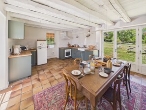 Eine Küche mit Esstisch, der für eine Mahlzeit gedeckt ist, einem Kühlschrank, einer Mikrowelle und einem Spülbecken.