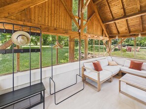 Ein Holzinnenraum mit einem weißen Sofa, einem hängenden Haken für Hüte und Blick ins Freie.