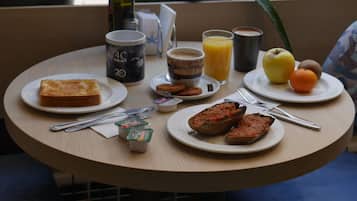 Una mesa redonda con alimentos para el desayuno, como tostadas, huevos y jugo de naranja.